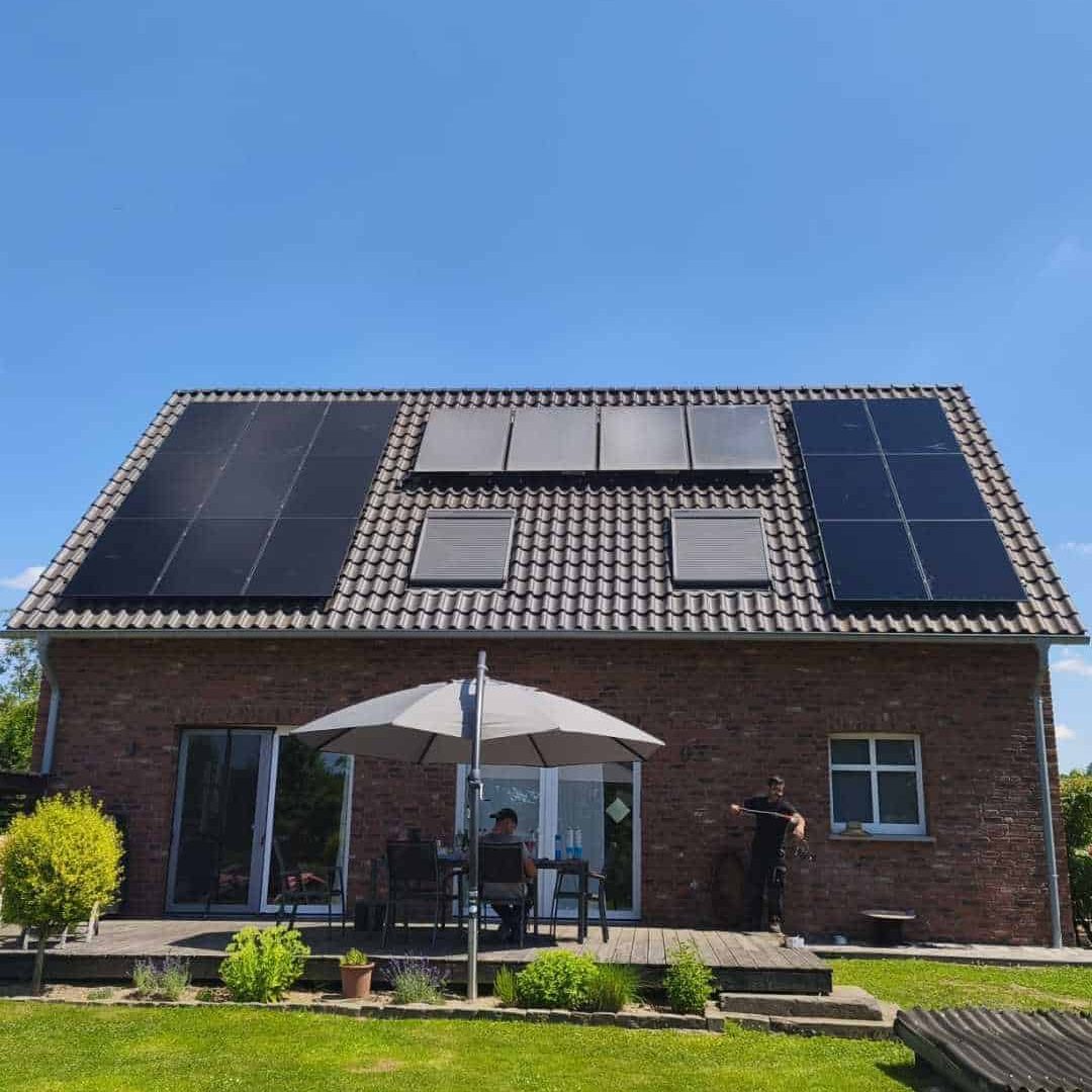 Einfamilienhaus mit Solaranlagen auf dem Dach, Terrasse mit Sonnenschirm und Garten mit Pool.